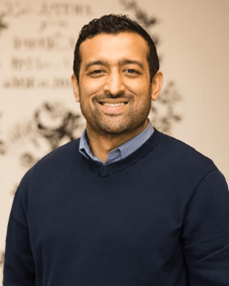 Dr. Rajat Shetty wearing a collared shirt and sweater and smiling for the camera